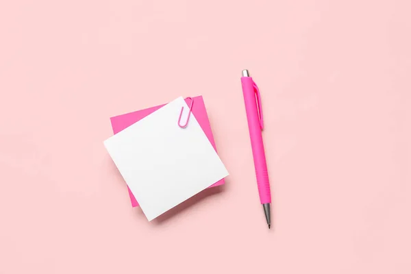 粉红背景的带有纸夹和钢笔的薄薄的便条 — 图库照片