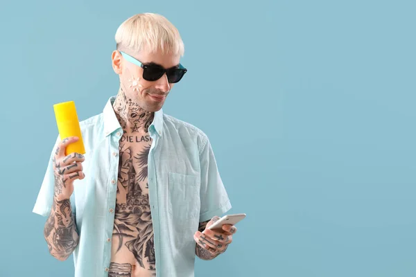 Hombre Tatuado Con Teléfono Crema Protector Solar Sobre Fondo Azul — Foto de Stock