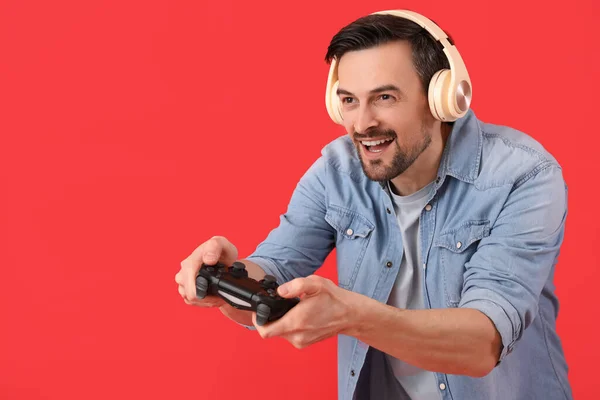 Knappe Man Hoofdtelefoon Met Game Pad Rode Achtergrond — Stockfoto