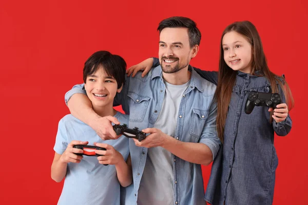 Μικρά Παιδιά Τον Πατέρα Τους Παίζουν Βιντεοπαιχνίδι Κόκκινο Φόντο — Φωτογραφία Αρχείου