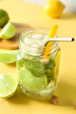 Sarı arka planda bir kavanoz lezzetli mojito.