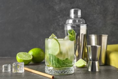 Bir bardak taze mojito, çalkalayıcı ve arka planda jigger.
