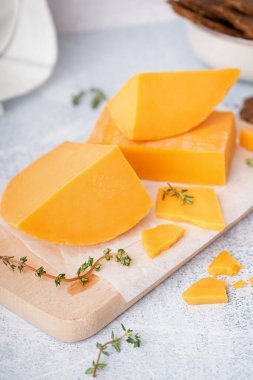 Hafif arkaplanda lezzetli çedar peyniri ve kekik olan tahta, yakın plan.