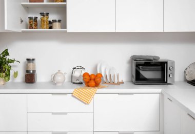 Mutfakta yiyecek ve mutfak aletleri olan beyaz tezgahlar.