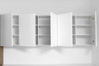 Mutfaktaki ışık duvarında asılı beyaz dolaplar.