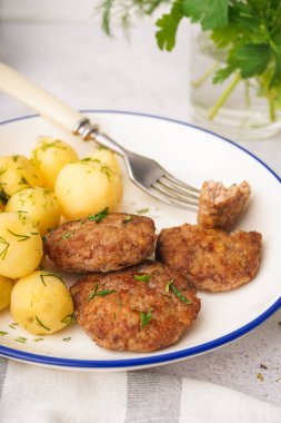 Pirzola tabağı, haşlanmış bebek patatesler ve mutfaktaki beyaz grunge masasında dereotu.