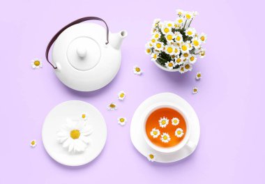 Bir fincan doğal papatya çayı ve leylak arkaplanda çiçekler.