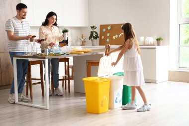 Mutfakta çöpleri geri dönüşüm kutularıyla sıralayan aile.