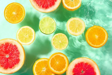 Turkuaz arka planda sudaki farklı narenciye dilimleri