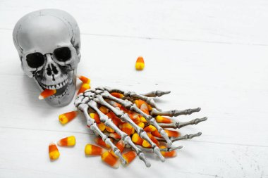 Lezzetli Cadılar Bayramı şekerleri, iskelet eller ve kafatası hafif ahşap arka plan, yakın plan