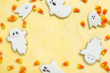 Lezzetli cadılar bayramı şekerlerinden ve sarı arka planda kurabiyelerden yapılmış çerçeve