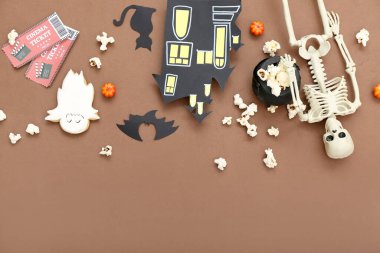 Lezzetli patlamış mısır, kağıt dekor, iskelet ve sinema biletleriyle kahverengi arka planda kompozisyon. Cadılar Bayramı