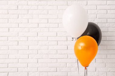 Aydınlık tuğla duvarın yanında farklı Cadılar Bayramı balonları