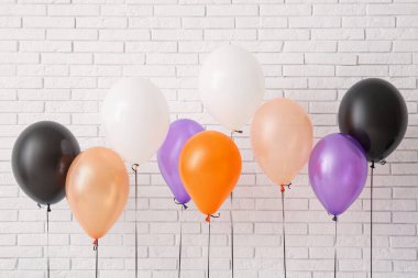 Aydınlık tuğla duvarın yanında farklı Cadılar Bayramı balonları