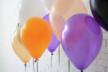 Aydınlık tuğla duvarın yanında farklı Cadılar Bayramı balonları.