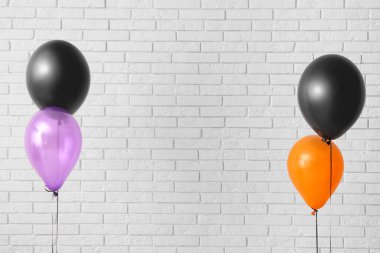 Aydınlık tuğla duvarın yanında farklı Cadılar Bayramı balonları