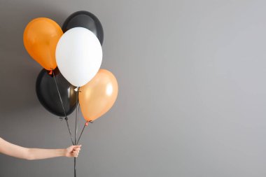 Gri arka planda farklı Cadılar Bayramı balonları olan kadın eli