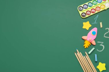 Yeşil karatahtanın üzerinde farklı bir kırtasiyeyle plastikten yapılmış roket.