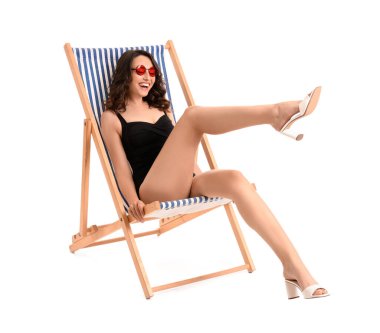 Güverte sandalyesinde beyaz arka planda genç bir kadın.