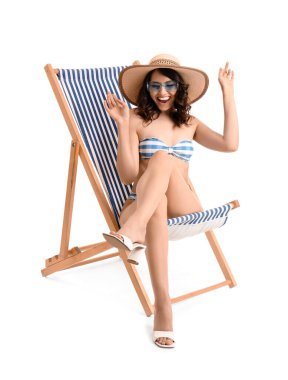 Güverte sandalyesinde beyaz arka planda genç bir kadın.