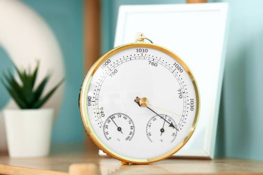 Aneroid barometer on wooden table in room, closeup clipart