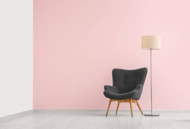 Pembe duvarın yanında gri koltuk ve standart lamba.