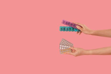 Farklı ilaç kutuları ve pembe arka planda su toplayan kadın elleri.