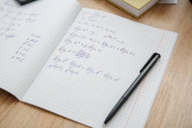 Hesap defterini matematik formülleri ve tahta masa üzerindeki kalemle aç