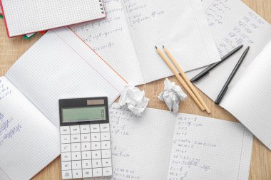 Matematik formülleri ve ahşap masadaki kırtasiye malzemeleriyle metin kitaplarını aç
