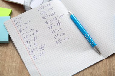 Matematik formülleri ve tahta masa üzerindeki kalemle metin defterini aç, kapat