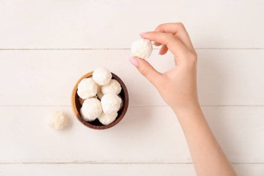 Beyaz ahşap masadan hindistan cevizi şekeri alan bir kadın.