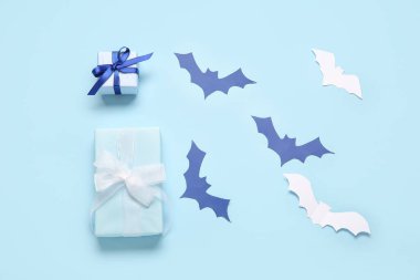 Cadılar Bayramı için mavi arka planda kağıttan yapılmış güzel hediye kutuları ve yarasalarla kompozisyon