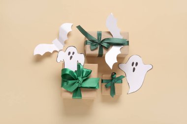 Bej arka planda güzel hediye kutuları ve Cadılar Bayramı dekoru olan kompozisyon