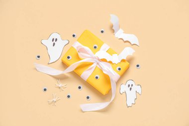 Bej arka planda güzel hediye kutusu ve Cadılar Bayramı dekoru olan kompozisyon