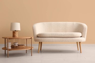 Sade beyaz kanepe ve bej duvarın yanında lamba olan kahve masası.