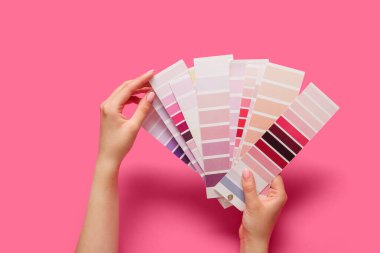 Pembe arkaplanda renk paletleri olan eller