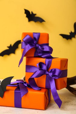 Cadılar Bayramı için turuncu arka planda kağıttan yapılmış güzel hediye kutuları ve yarasalar.