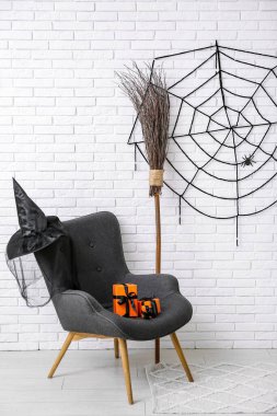 Hediye kutularıyla, süpürgesiyle, şapkasıyla ve ağıyla ışıklı tuğla duvarda asılı duran bir koltuk.