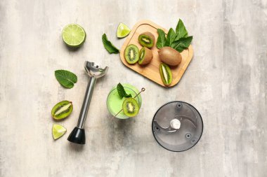 Glass of fresh kiwi smoothie with mint and lime on grey background
