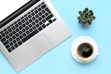 Modern dizüstü bilgisayar, kahve fincanı ve renkli bitki örtüsü.