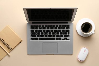 Modern dizüstü bilgisayar, bilgisayar faresi, defter ve kahve fincanı.