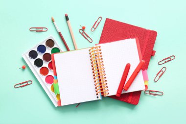 Turkuaz arka plan üzerine farklı okul kırtasiyesi ve not defterleri
