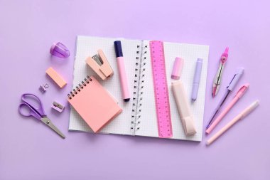 Mor arka planda farklı okul kırtasiyesi ve defter