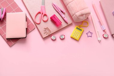 Pembe arka planda farklı okul kırtasiyesi ve not defterleri
