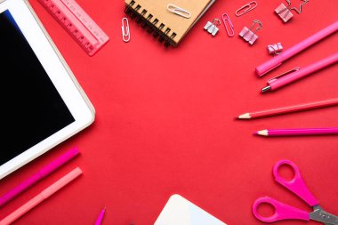 Kırmızı arkaplanda farklı kırtasiye ve tablet bilgisayardan yapılmış çerçeve