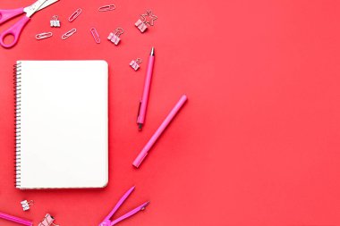 Kırmızı arkaplanda boş defteri olan bir kırtasiye seti