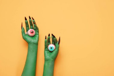 Turuncu arka planda gözü olan cadının yeşil elleri. Cadılar Bayramı