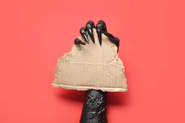 Kırmızı zemin üzerinde boş kağıt çarşaf ile cadının kara eli. Cadılar Bayramı