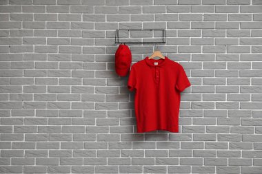 Gri duvarda asılı şık kırmızı tişört ve kapak