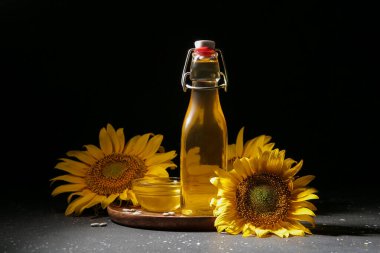 Siyah arka planda çekirdekleri olan bir şişe ve cam ayçiçeği yağı.